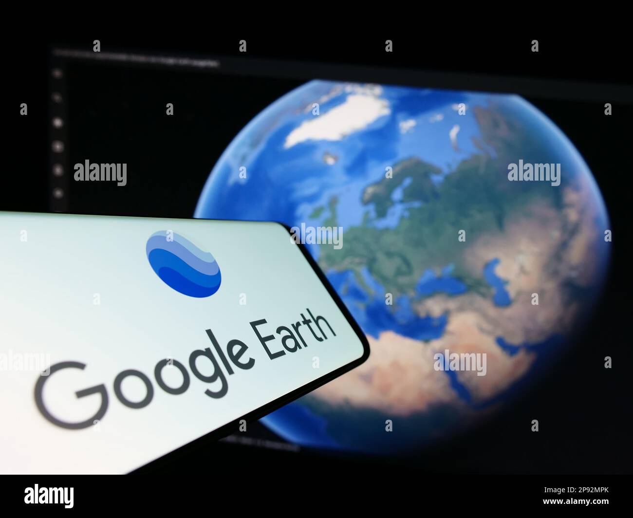 Mobiltelefon mit Logo der Satellitenbildsoftware Google Earth auf dem Bildschirm vor der Website. Fokus auf die rechte Seite des Telefondisplays. Stockfoto