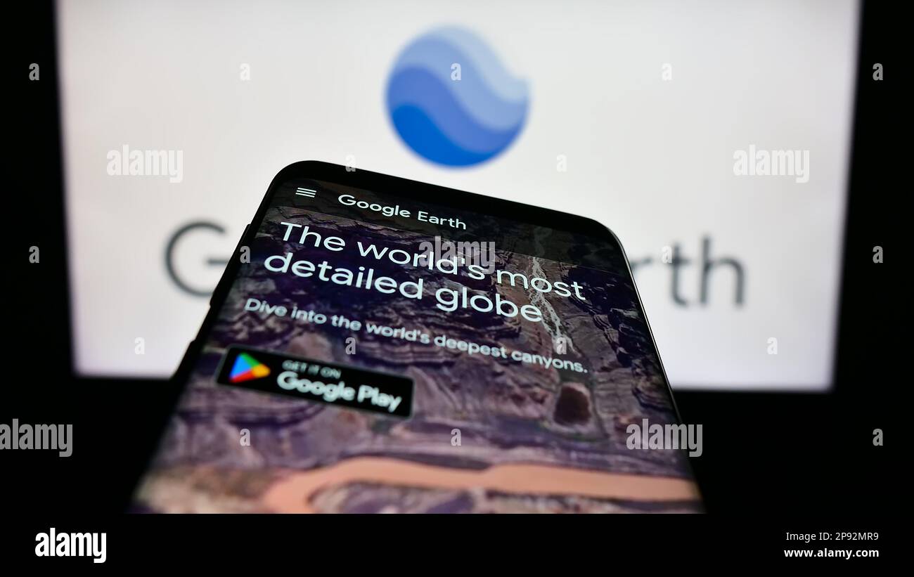 Smartphone mit Website der Satellitenbildsoftware Google Earth auf dem Bildschirm vor dem Logo. Fokus auf oberer linker Seite des Telefondisplays. Stockfoto