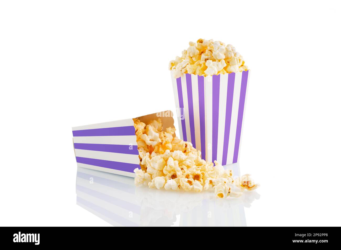Zwei violett-weiß gestreifte Eimer mit leckerem Käsepopcorn, isoliert auf weißem Hintergrund. Schachtel mit Streuung von Popcornkörnern. Filme, Kino Stockfoto