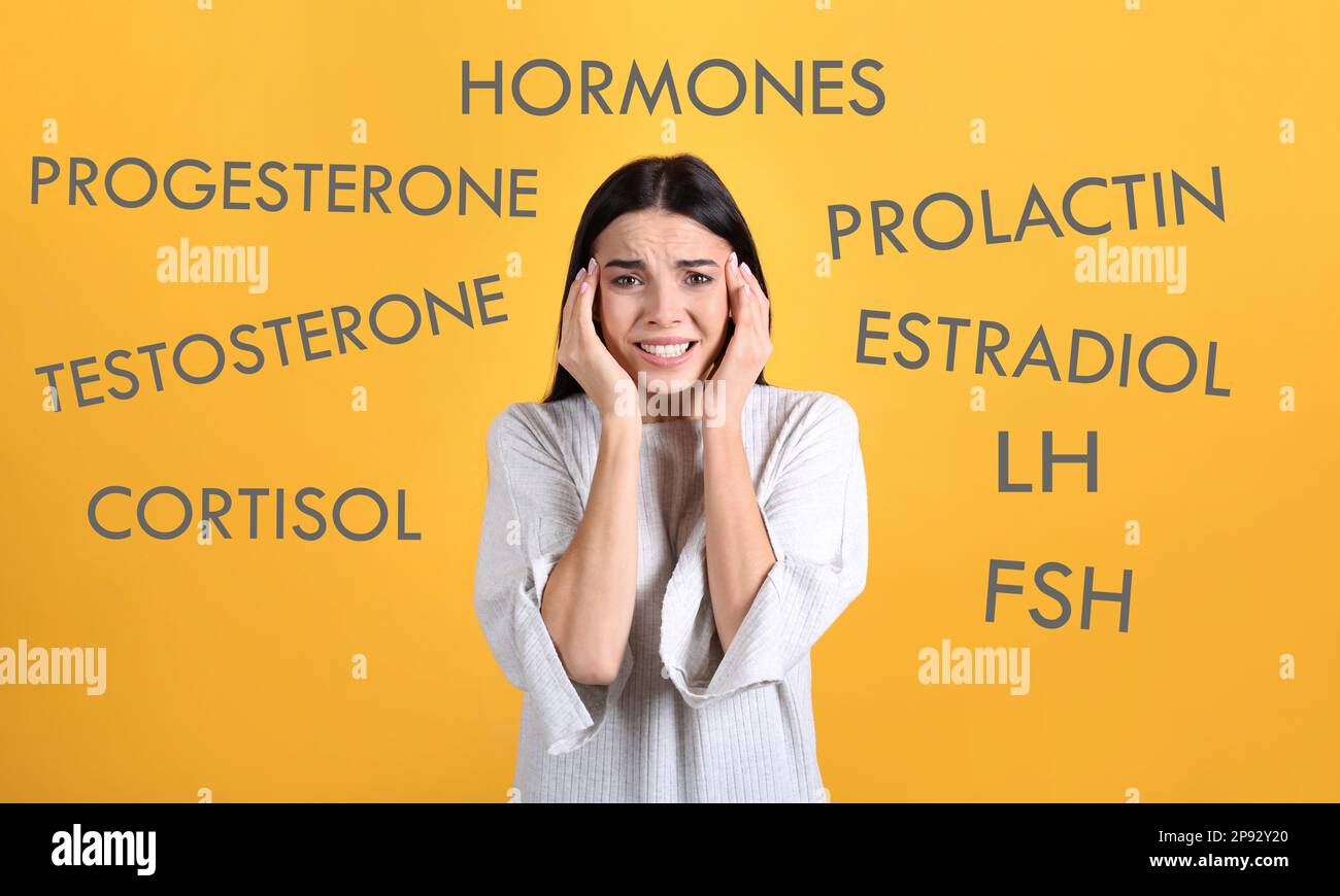 Hormonstörungen. Gestresste junge Frau und andere Wörter auf gelbem Hintergrund Stockfoto