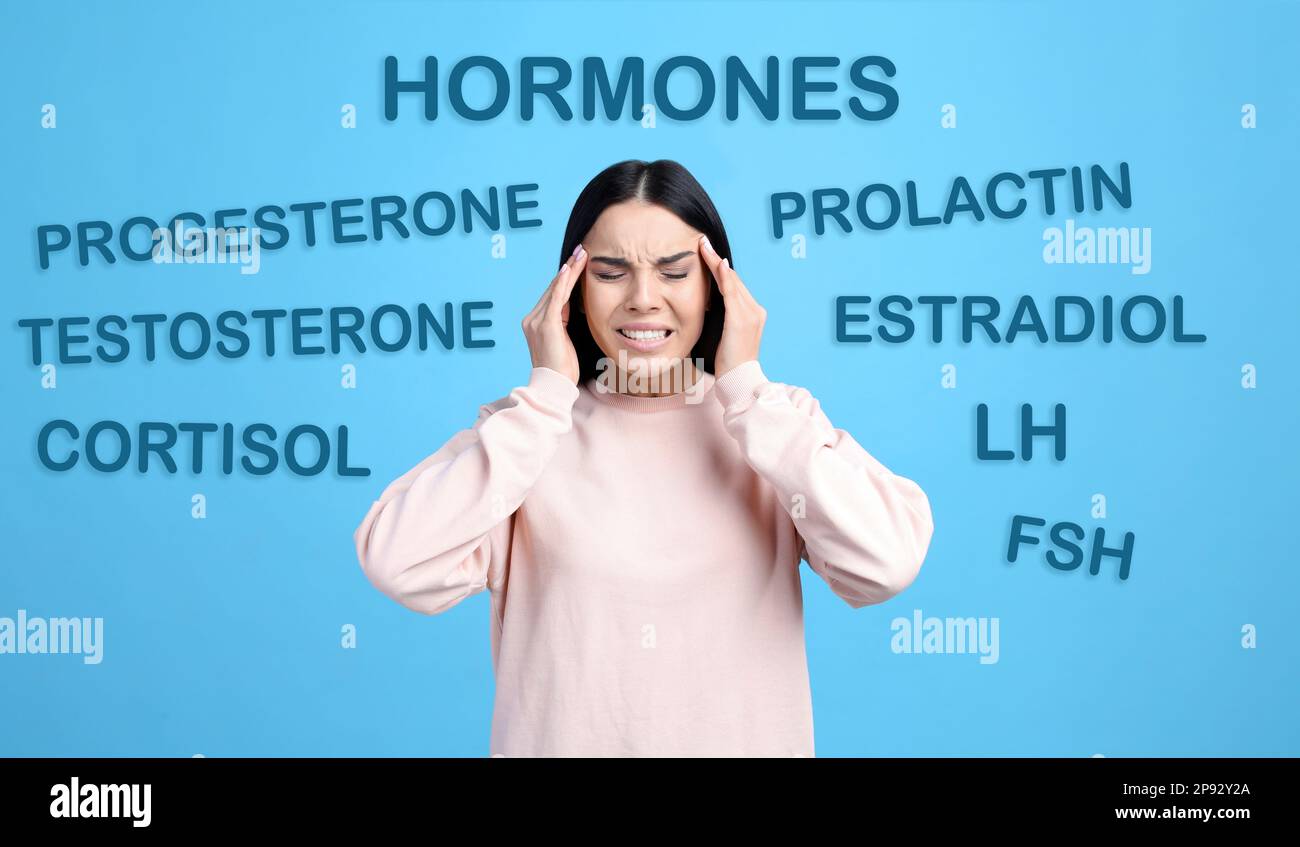 Hormonstörungen. Gestresste junge Frau und andere Wörter auf hellblauem Hintergrund Stockfoto