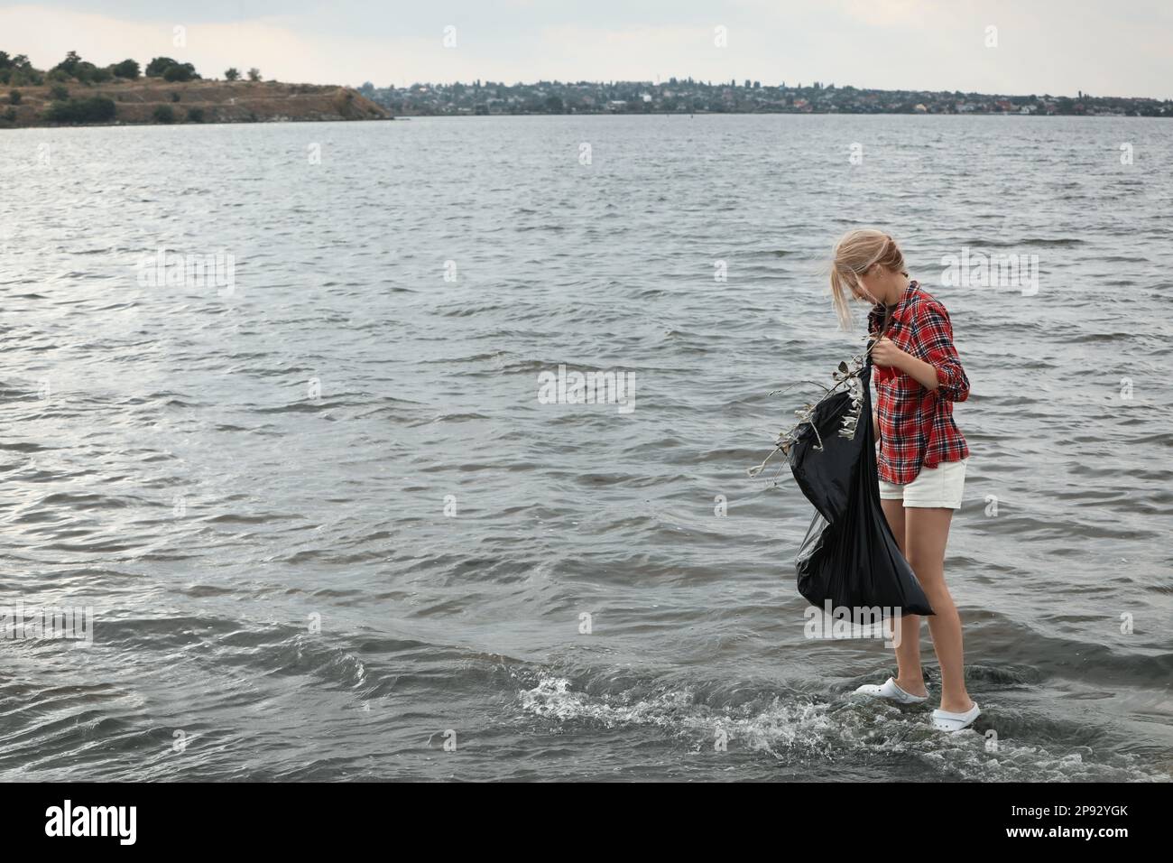 Frau mit Müllsack, die Müll am Strand sammelt. Platz für Text Stockfoto