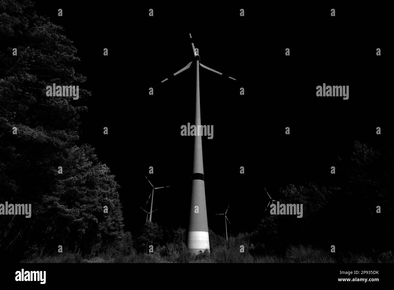 Windturbinen in einem Wald, schwarzer dunkler Himmel, Schwarzweiß-Fotografie Stockfoto