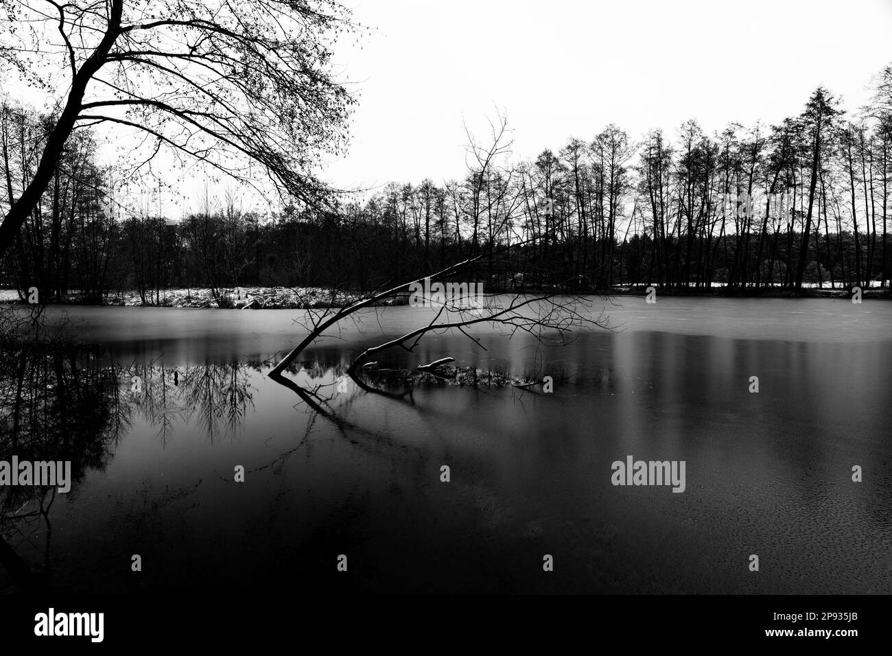Teilweise gefrorener See im Winter, Schnee liegt am Ufer, Schwarzweiß-Fotografie, Schwarzweiß-Fotografie Stockfoto