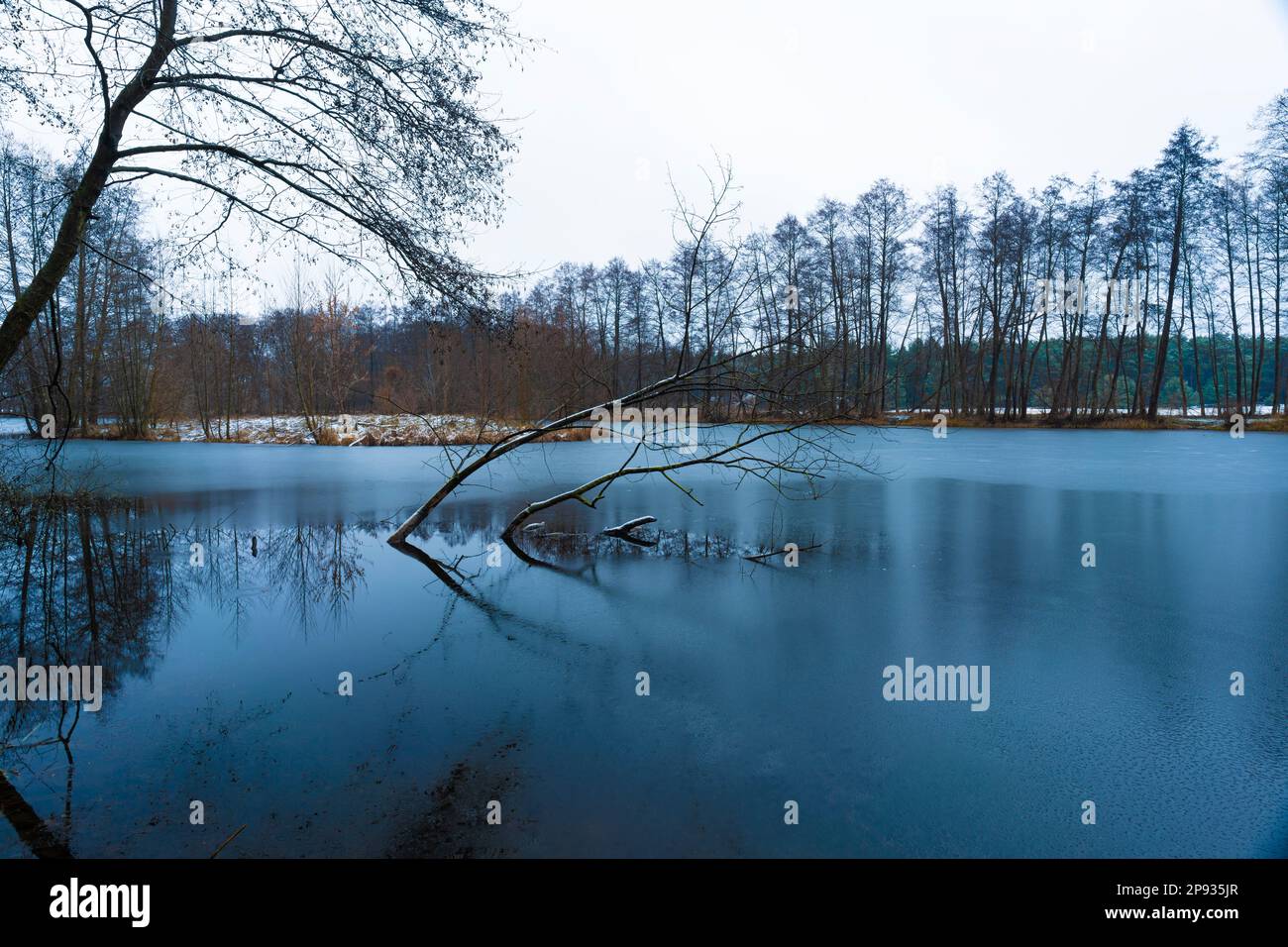 Teilweise gefrorener See im Winter, Schnee liegt am Ufer, Schwarzweiß-Fotografie Stockfoto