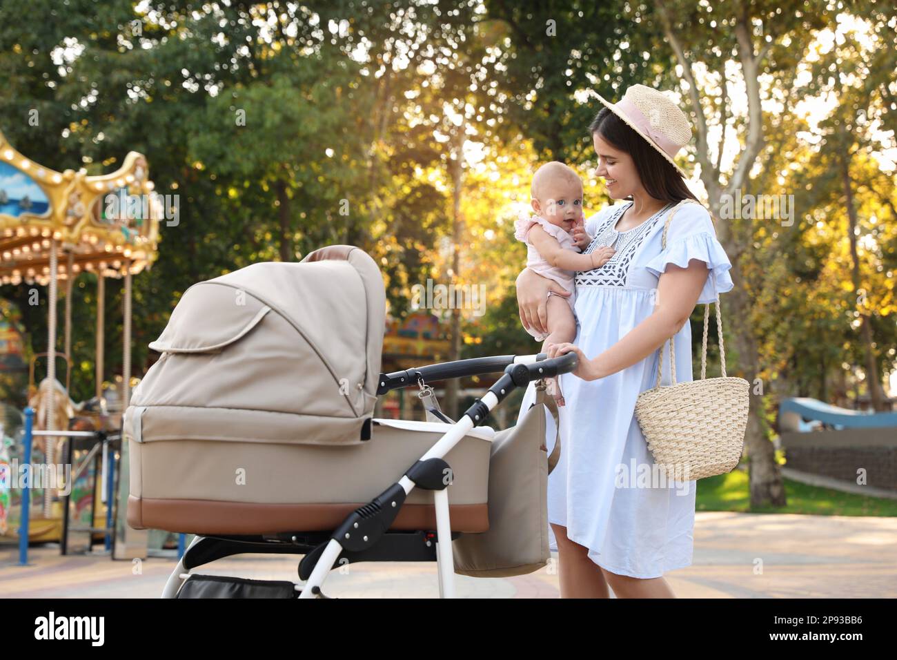 Glückliche Mutter mit Baby und Kinderwagen im Park Stockfoto