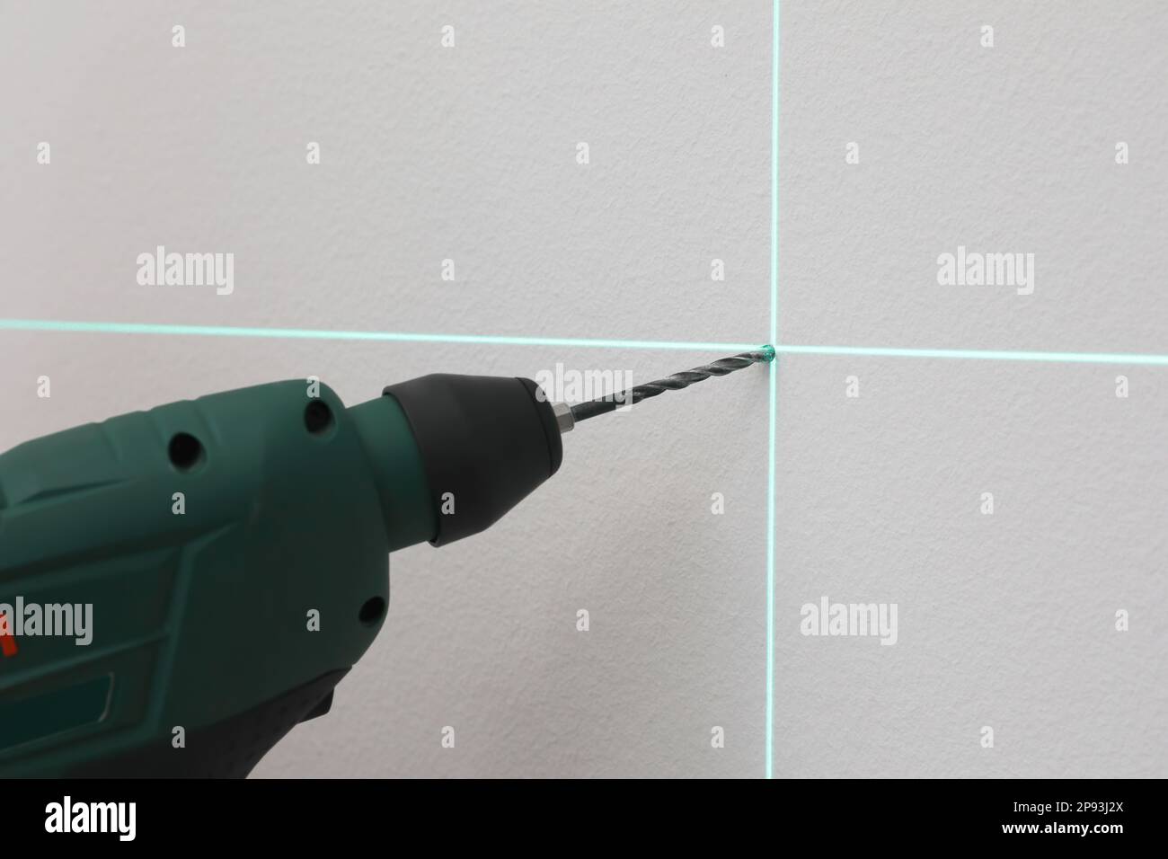 Verwendung von Kreuzlinien-Laser-Nivelliergeräten für genaue Messungen und Bohren von Löchern in grauen Wänden, Nahaufnahme Stockfoto