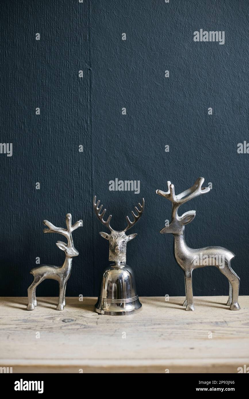 Drei kleine silberne Hirschfiguren auf einem Holzregal Stockfoto