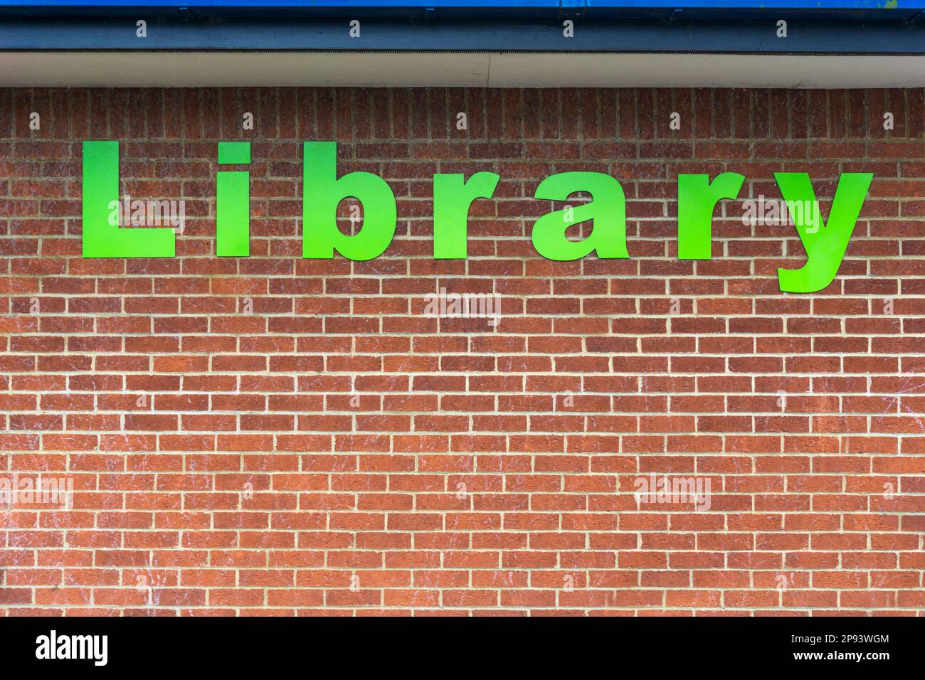 Das Wort Bibliothek in großen grünen Buchstaben auf der Ziegelwand einer öffentlichen Bibliothek. Stockfoto