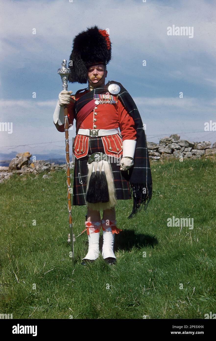1960er, historisch, Highland Drum Major in seiner Uniform und mit zeremoniellen Pfeffer, steht für sein Foto Highland, Schottland, Großbritannien. Stockfoto