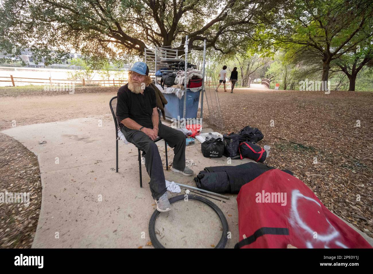 Austin, Texas, USA. 9. März 2023. Ein Obdachloser, der nicht identifiziert werden wollte, sitzt am 9. März 2023 bei den meisten seiner Sachen auf dem Wander- und Radweg entlang der Nordküste des Lady Bird Lake in der Innenstadt von Austin. Der Mann, der seit etwa 9 Monaten an der Küste zeltet, wurde schließlich von Crews gebeten, zu gehen, die einen geteilten Zaun bauen und Beleuchtung hinzufügen, nachdem er kürzlich ertrunken war. (Kreditbild: © Bob Daemmrich/ZUMA Press Wire) NUR REDAKTIONELLE VERWENDUNG! Nicht für den kommerziellen GEBRAUCH! Stockfoto