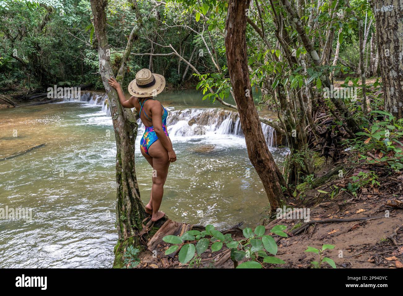 Nordamerika, Karibik, Großantillen, Hispaniola, Dominikanische Republik, Monte Plata Provinz, Bayaguana, attraktive Frau, die sich am Fluss gegen einen Baum lehnt Stockfoto