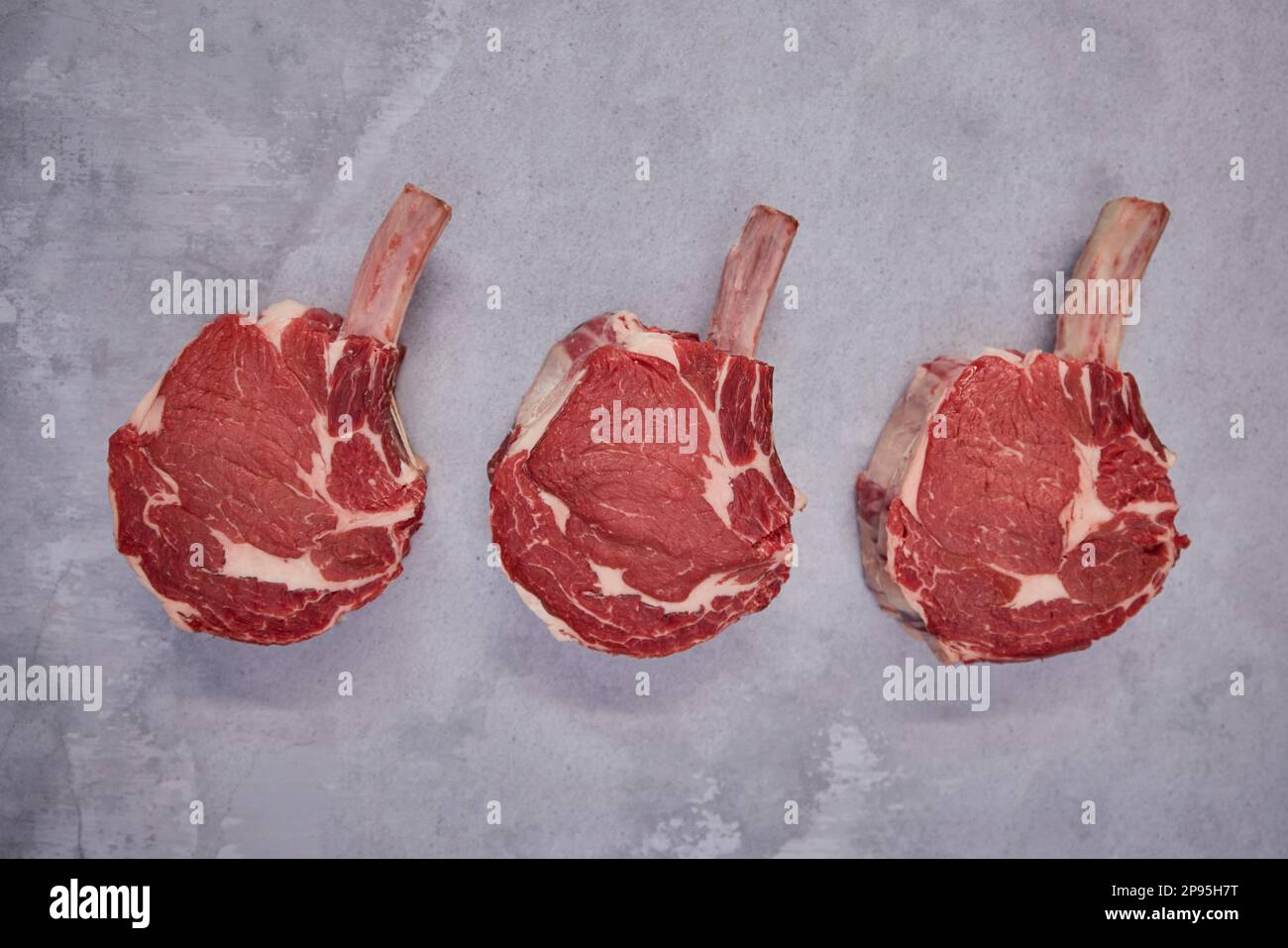 Aufnahme von Tomahawk Beef Steaks über Kopf im Hintergrund in Butcher's Shop Display Stockfoto