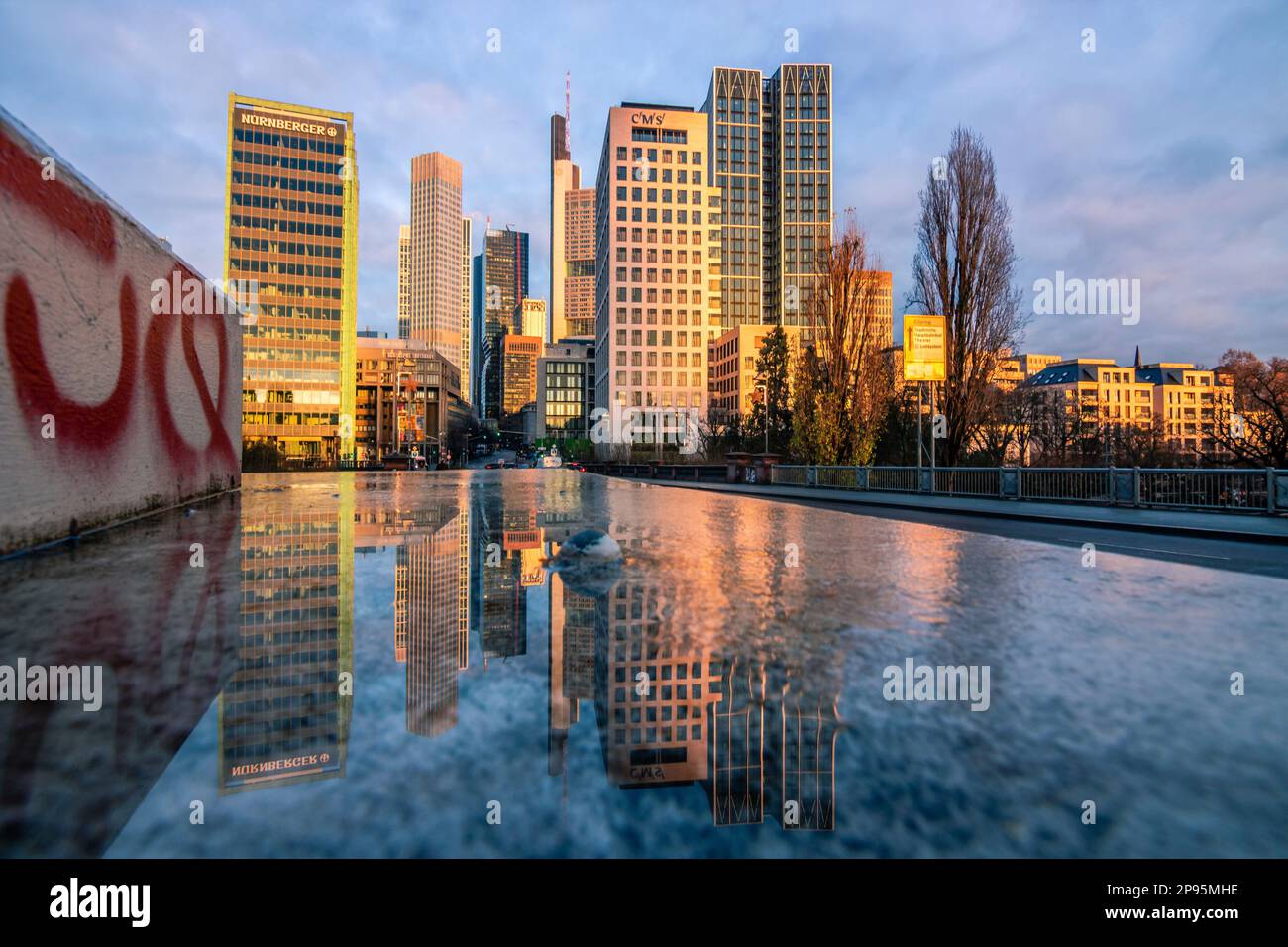 Reflexionen in Frankfurt am Main. Die Stadt, Straßen und Wolkenkratzer spiegeln sich nach Regen in den Pfützen der Straßen wider. Bankenviertel und Wolkenkratzer am Morgen Stockfoto