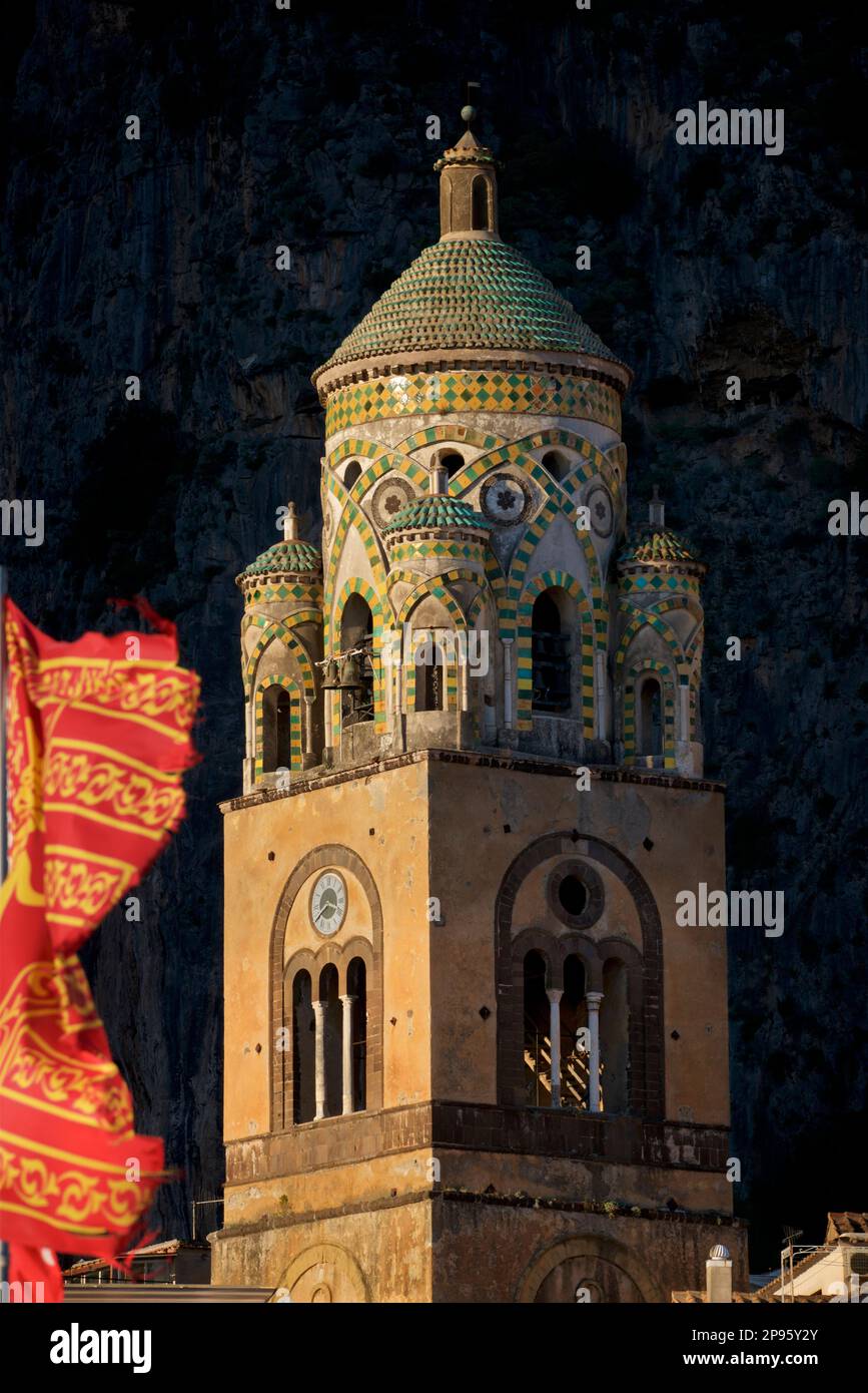 Glockenturm des Duomo di Sant Andrea (St. Andrew's Cathedral). Amalfi, Salerno, Italien Amalfiküste. Die Kathedrale, die im 9. Und 10. Jahrhundert begann, wurde mehrmals ergänzt und umgestaltet und überlagert arabisch-normannische, gotische, Renaissance- und Barockelemente, Und schließlich eine neue normannisch-arabisch-byzantinische Fassade aus dem 19. Jahrhundert. Die venitianische Flagge weht im Wind Stockfoto