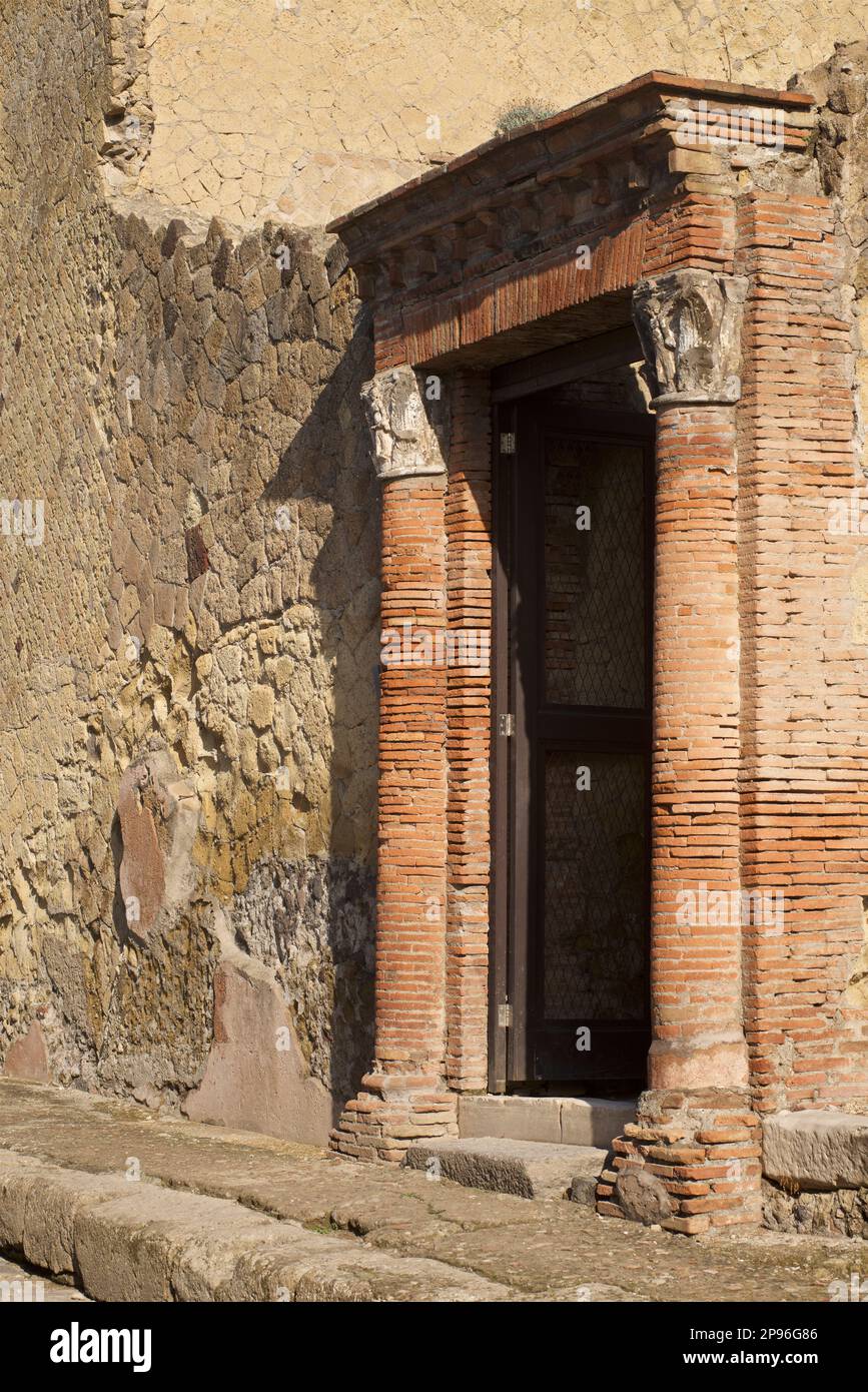 Herculaneum aufgedeckt. Herculaneum wurde beim Ausbruch des Vesuv im Jahre 79 v. Chr. unter vulkanischer Asche und Bimsstein begraben. Ercolano, Kampanien, Italien Detail aus Stein und Backsteinwand. Mit Türrahmen mit Backsteinsäulen und Großbuchstaben Stockfoto