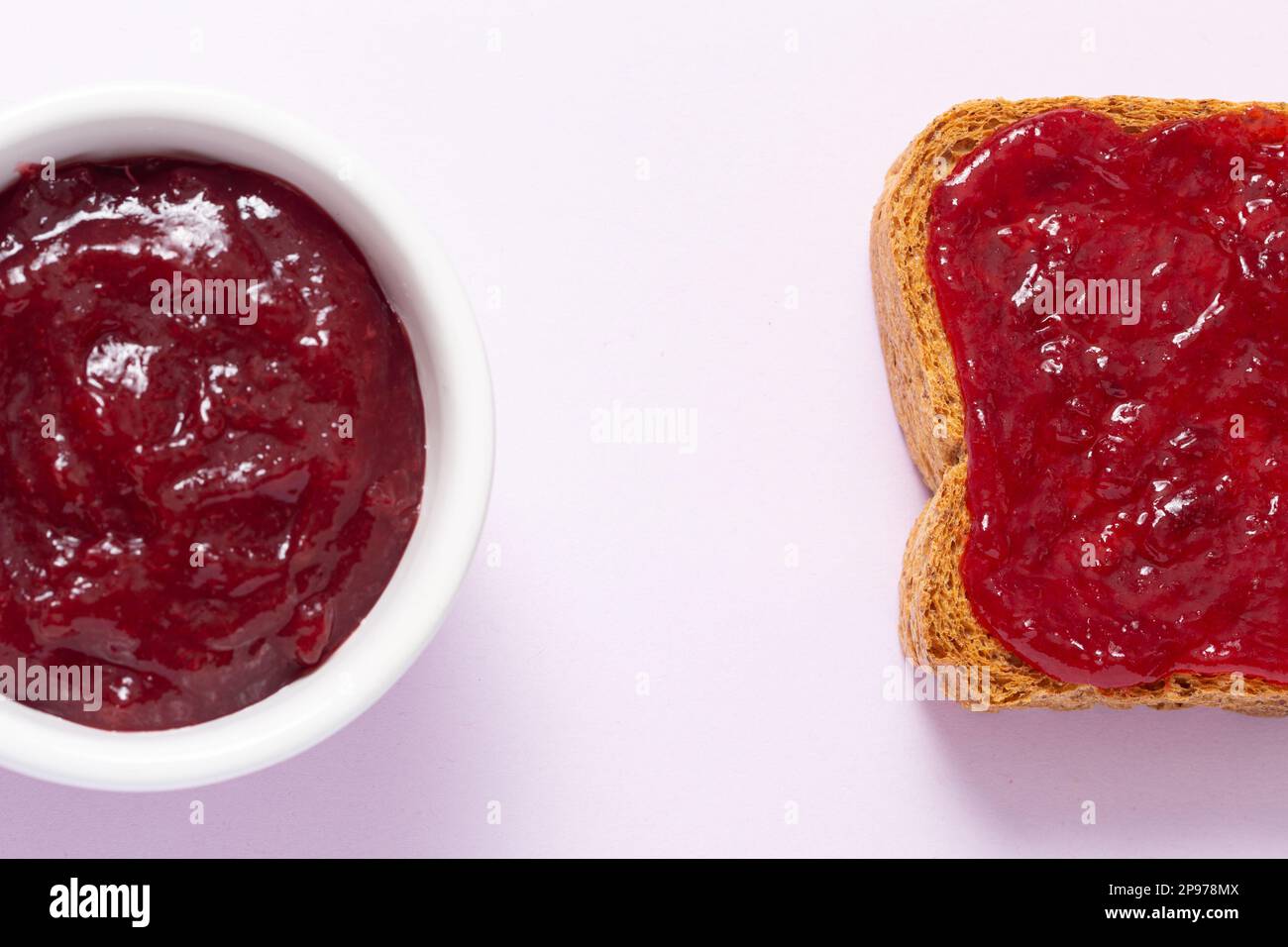Genießen Sie die köstliche Kombination aus geröstetem Brot, das großzügig mit süßer Pflaumenmarmelade gesäumt wird, aus der verlockenden Vogelperspektive Stockfoto