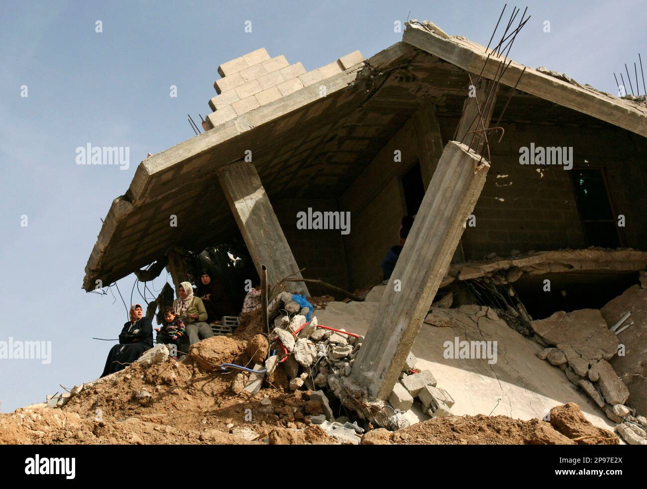 A Palestinian family sits on the rubble of their home in a devastated ...