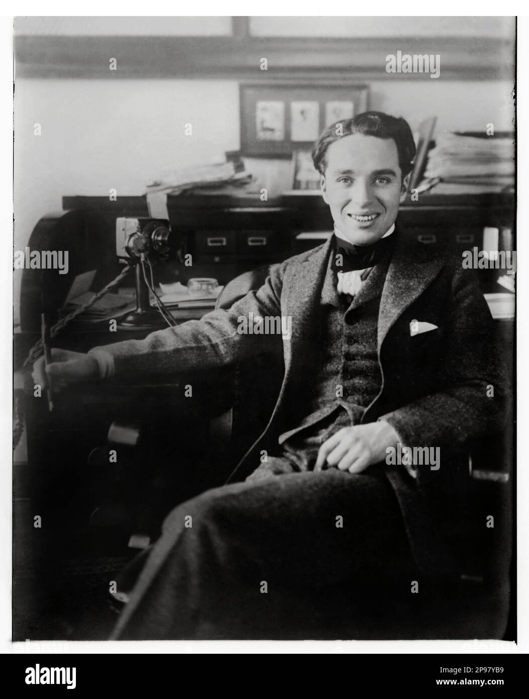 1915 Ca : der gefeierte englische Schauspieler und Filmregisseur CHARLES CHAPLIN ( 1889 - 1977 ) - CINEMA MUTO   SILET MOVIE - Portrait - ritratto - regista cinematografico - attore - comico - Schreibtisch - scrittoio - scrivania - Telefon - Telefon - Telefon - Telefon - Telefon - ufficio - Büro - lächeln - sorriso --- Archivio GBB Stockfoto