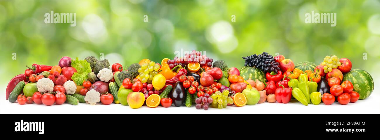 Bunte Beeren, Obst und Gemüse auf grünem, verschwommenem Hintergrund. Stockfoto