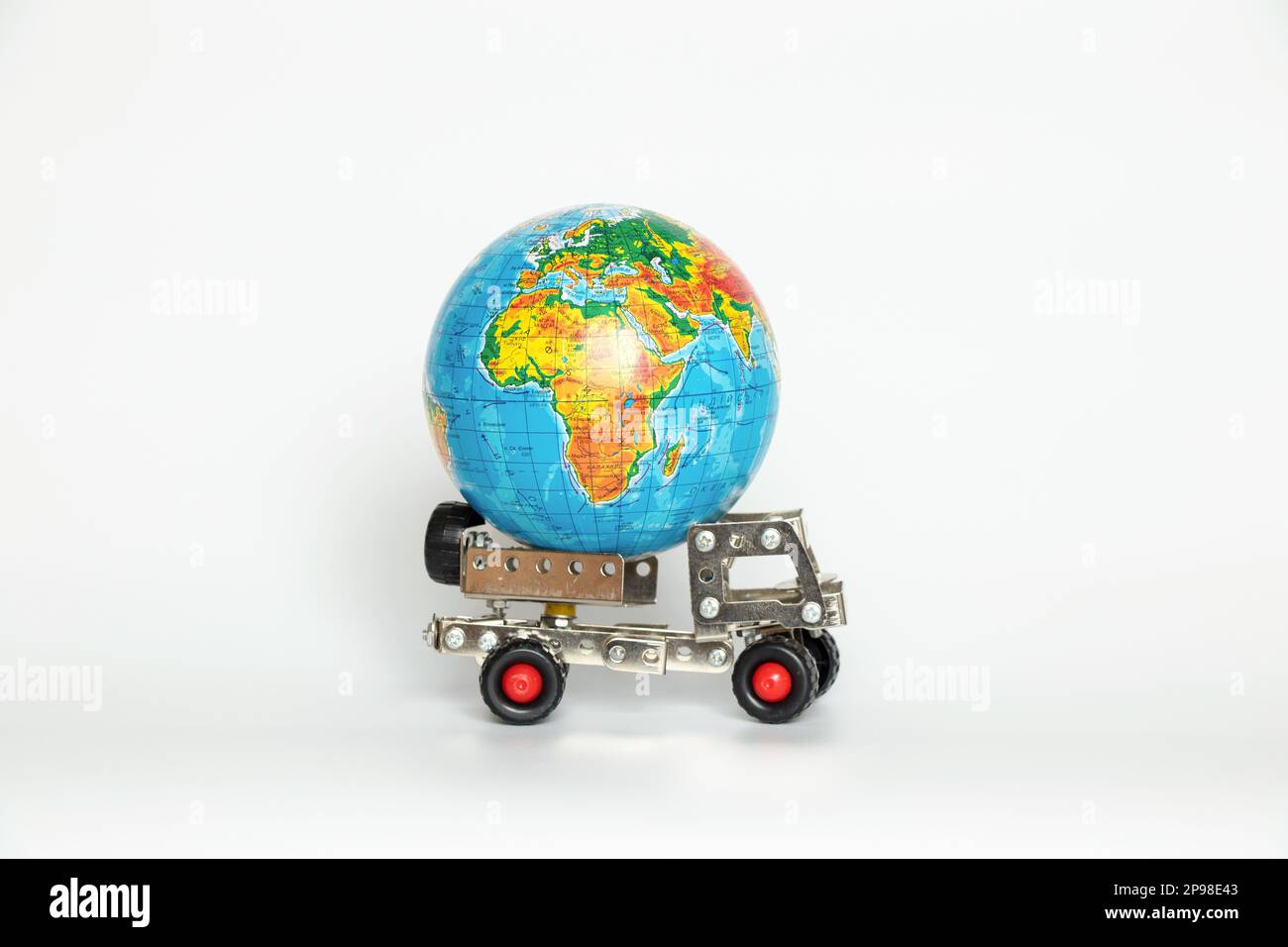 Globus auf einem kleinen Kinderwagen auf weißem Hintergrund, internationaler Transport, Logistik und Lieferung Stockfoto