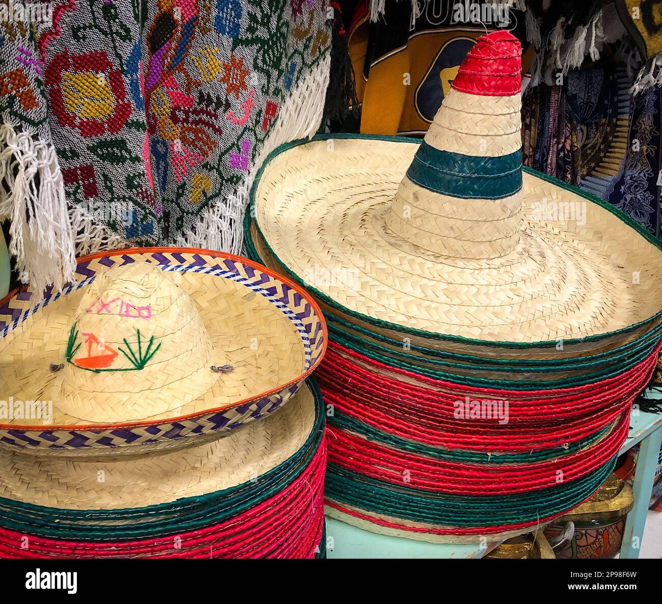 Stroh-Sombreros in vertikalen Stapeln, zum Verkauf in einem Touristenladen mit Artikeln aus Mexiko. Stockfoto