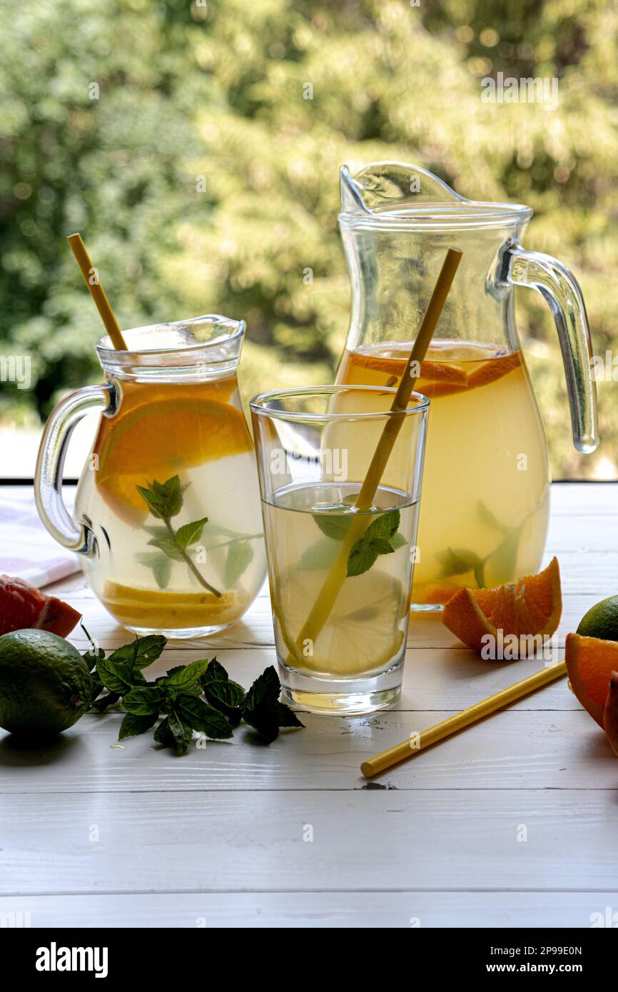 Zubereitung von Limonadetrinken. Limonade in einem Krug und Zitrone und Limette und Minze. Vertikales Foto Stockfoto