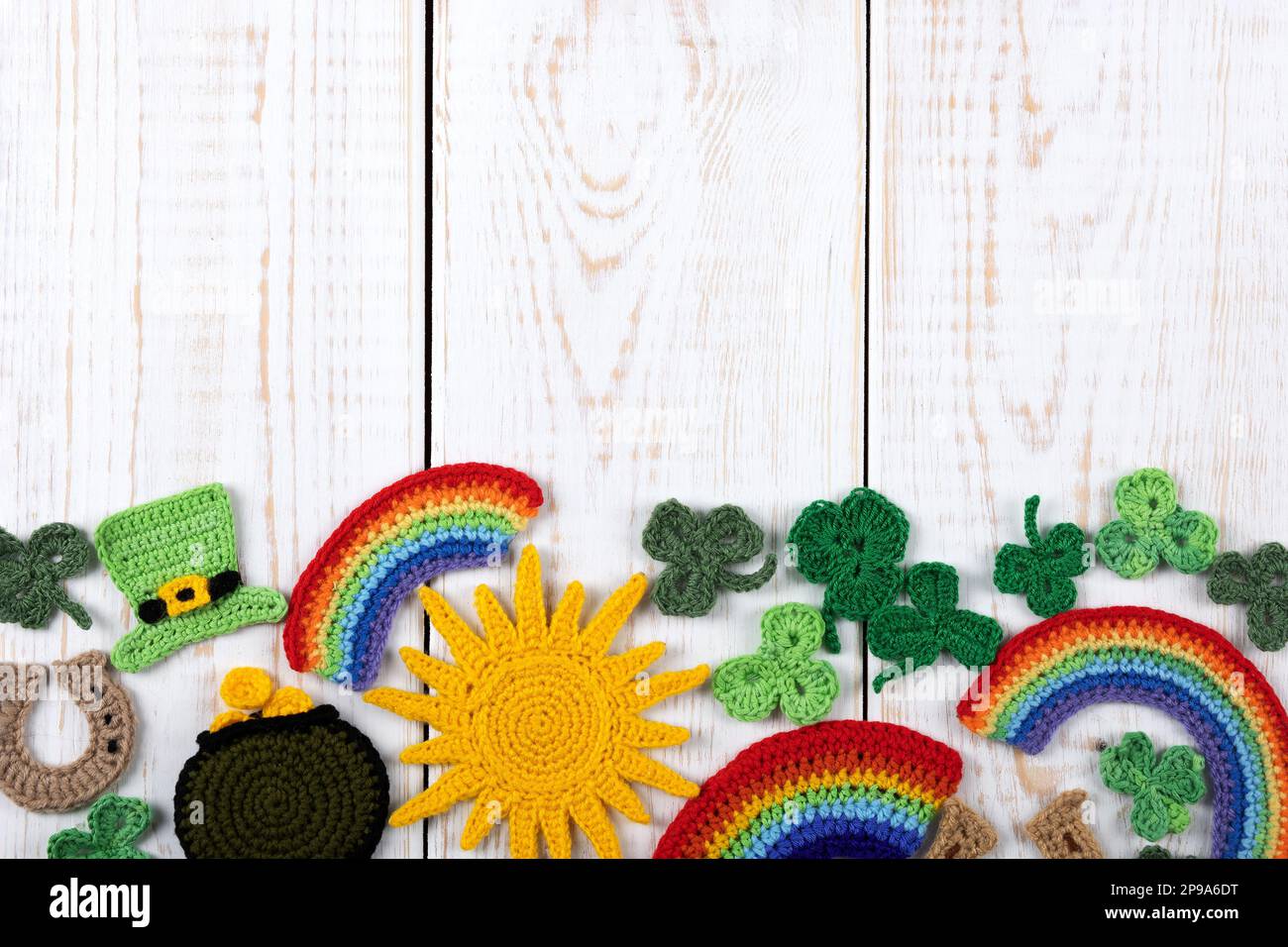 St. Patrick's Day Konzept. Gestrickte Komposition aus grünem Hut, Hufeisen, Sonne, Regenbogen und grünen Shamrocks auf weißem Holzhintergrund. Kopie SPA Stockfoto