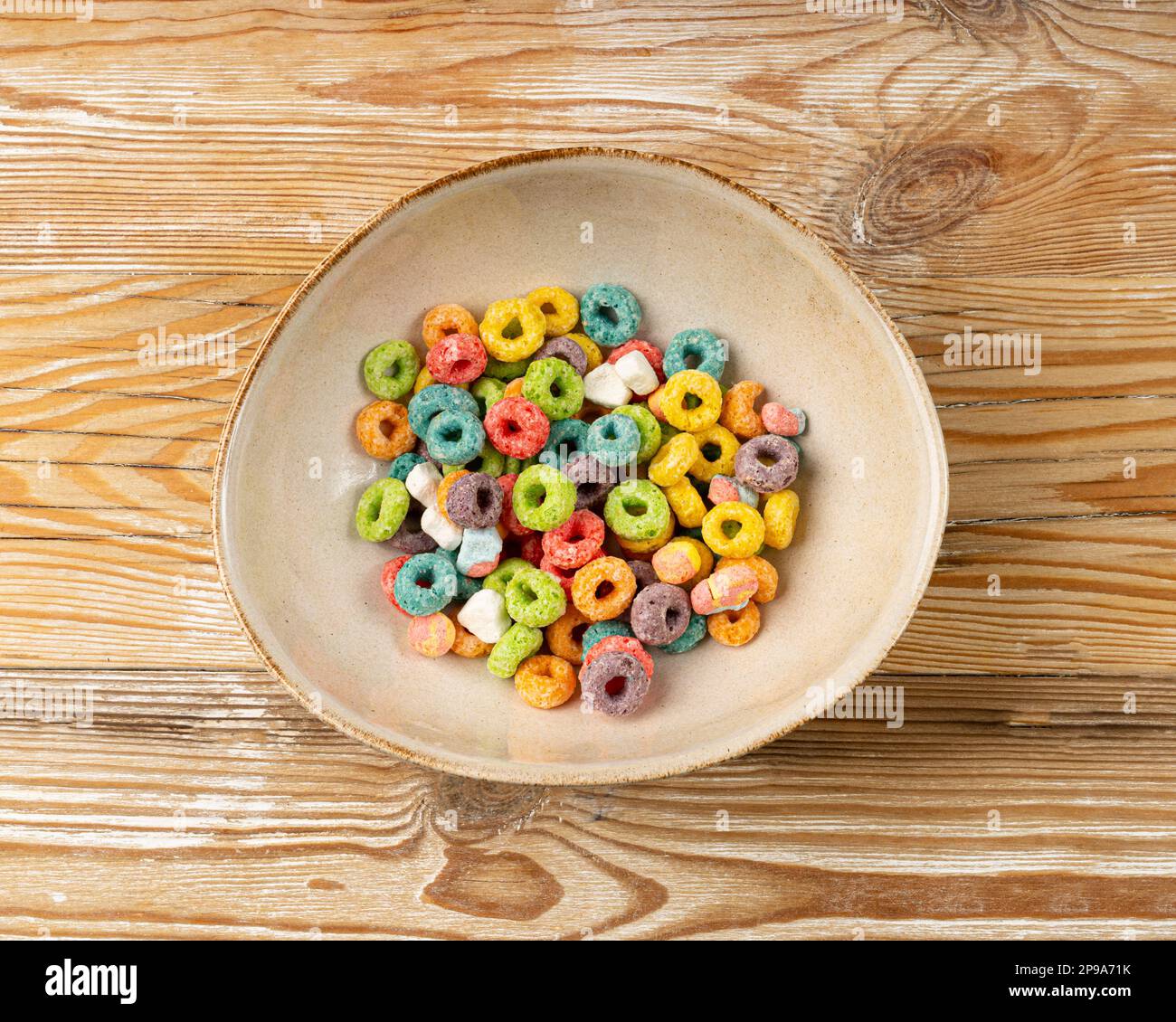 Bunte Frühstücksringe, Fruit Loops, fruchtige Cerealien-Ringe mit Marshmallows, bunte Corn Cerealien auf Holzhintergrund Stockfoto