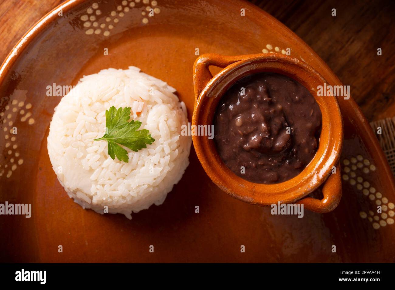 Beans and Rice serviert auf einem hausgemachten mexikanischen Tonteller. Sehr beliebte Speisen in Lateinamerika und weit verbreitet als Hauptzutat oder Begleitmittel Stockfoto