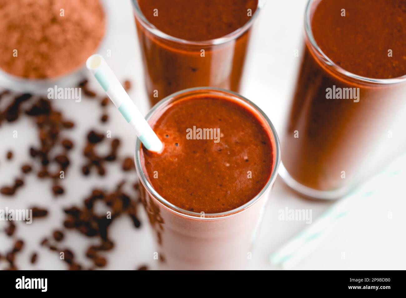 Drei Kaffee-Mocha Smoothies mit Papierhalm: Blick von oben auf eine Gruppe von Frühstücks-Smoothies mit Kaffee und Kakaopulver Stockfoto
