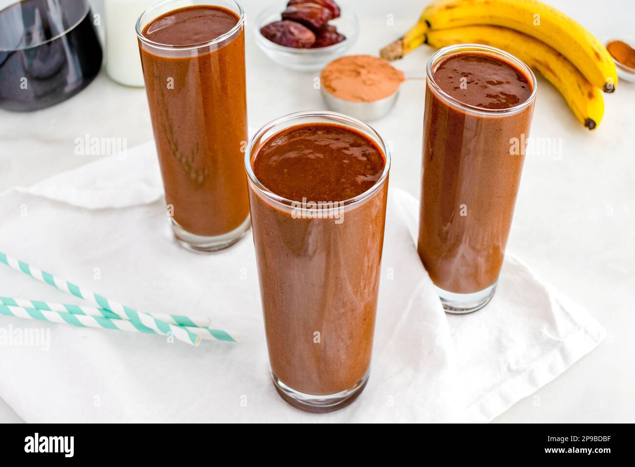 Drei Kaffee-Mocha Smoothies mit Papierhalm: Eine Gruppe von Frühstücks-Smoothies mit Kaffee, Kakaopulver und Bananen Stockfoto