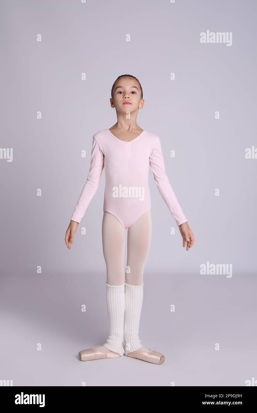 Kleine Ballerina, die Tanzbewegungen auf grauem Hintergrund macht Stockfoto