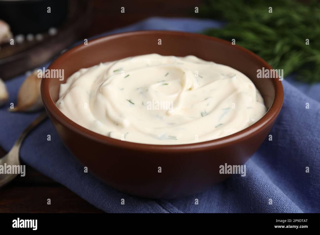 Leckere cremige Dill-Sauce in der Schüssel auf blauem Küchentuch, Nahaufnahme Stockfoto