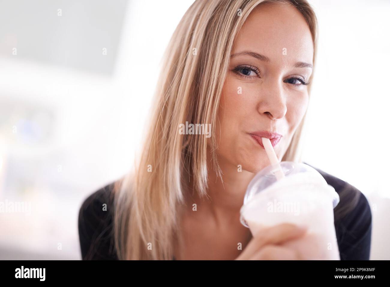 Gut bis zum letzten Tropfen. Porträt einer jungen Frau, die an einem Milchshake nippt. Stockfoto