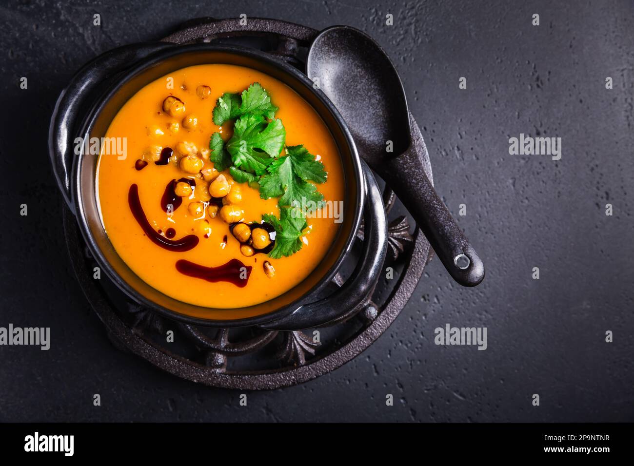 Cremige Kürbiscremesuppe mit Kürbissamenöl, gebackenen Kichererbsen und Koriander Stockfoto
