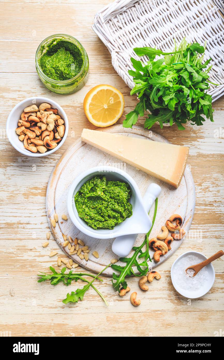 Hausgemachtes Rucola-Pesto mit Zutaten auf Holzhintergrund Stockfoto