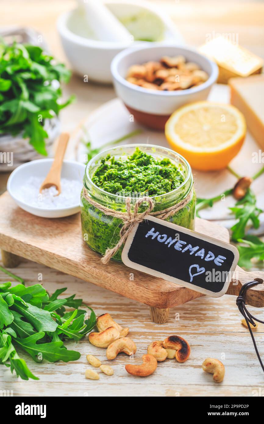 Hausgemachtes Rucola-Pesto mit Zutaten auf Holzhintergrund Stockfoto