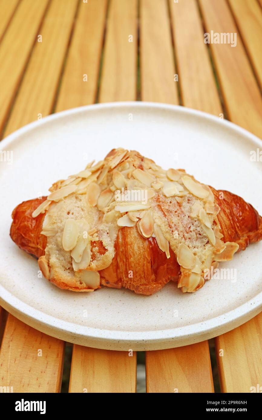 Köstliches französisches Mandel-Croissant-Gebäck auf einem Holztisch Stockfoto