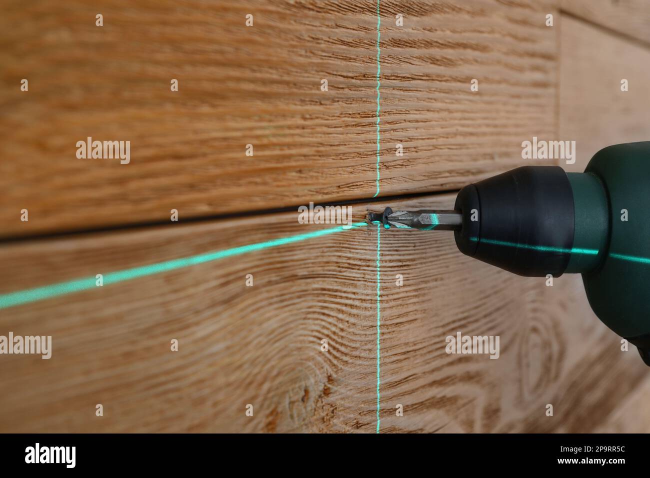 Verwendung von Kreuzlinienlaser-Nivelliergeräten für genaue Messung und Schraubanschluss in Holzwand, Nahaufnahme Stockfoto