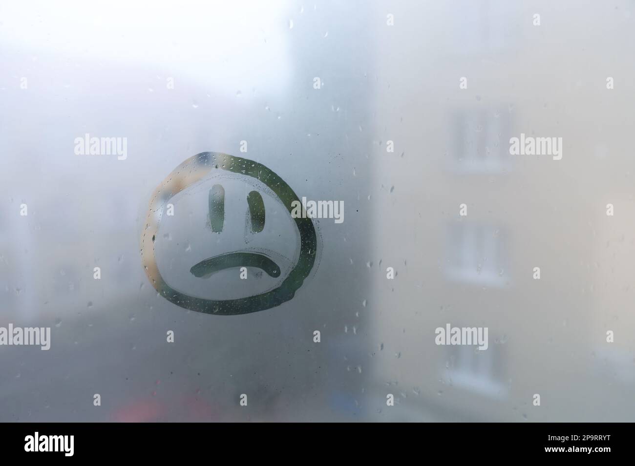 Trauriges Gesicht auf nebligem Fenster, Platz für Text. Regenwetter Stockfoto