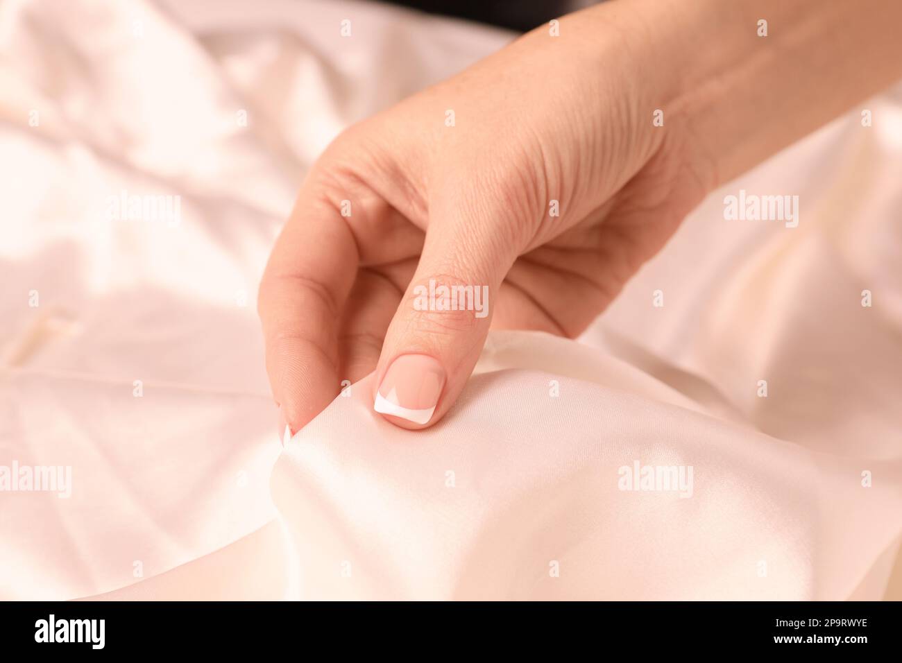 Frau berührt glatte, seidig weiße Stoffe, Nahaufnahme Stockfoto