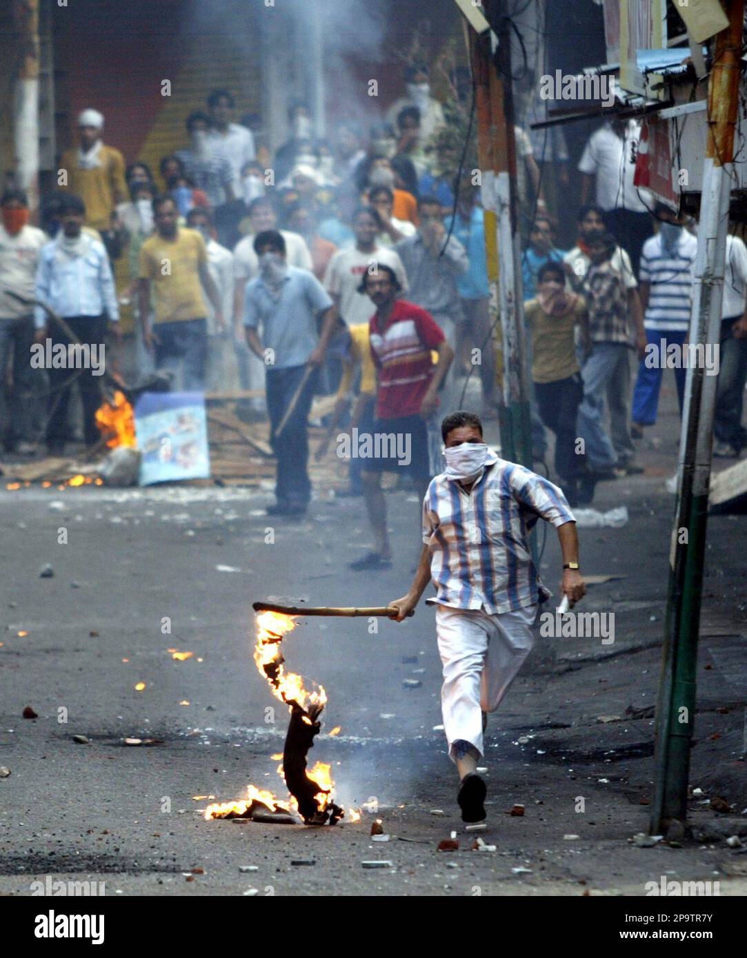 Hindu protestors burn tires and throw stones at police, unseen, in Jammu, India, Wednesday, July 30, 2008, as they protest against a recent government decision to cancel a land transfer to a Hindu shrine. (AP Photo/Channi Anand) Stockfoto