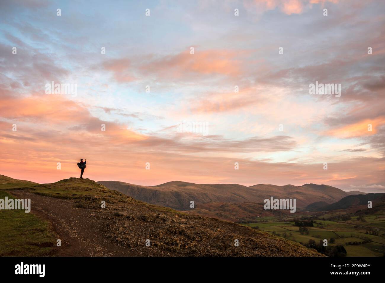 Wundervolle Sonnenuntergangslandschaft Bild der Aussicht von Latrigg fiel in Richtung Great Dodd und Stybarrow Dodd im Lake District mit einem Mann, der die Landschaft fotografierte Stockfoto