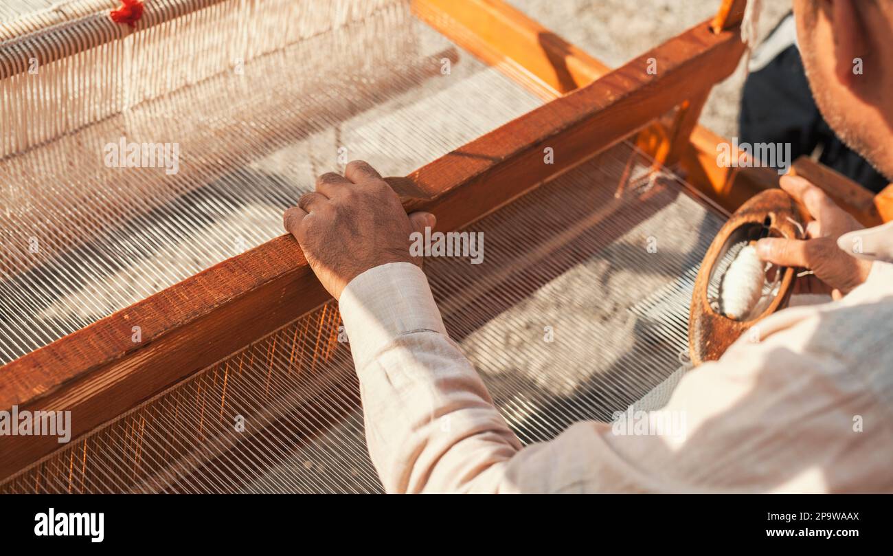 Ein Teppichweber, der den Webstuhl bereitstellt. Handgefertigte Textilgewebe, gewebt mit traditionellen Werkzeugen. Stockfoto