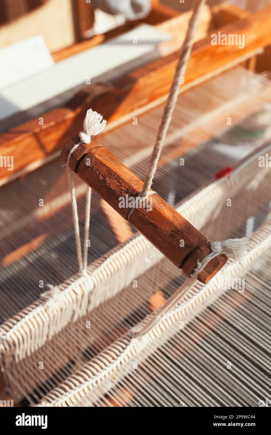Detaildarstellung der Webausrüstung auf dem antiken Holzkabelstrang und dem Shuttle zum Gewindestiften. Handgefertigte Textilgewebe, gewebt mit traditionellen Werkzeugen. Stockfoto