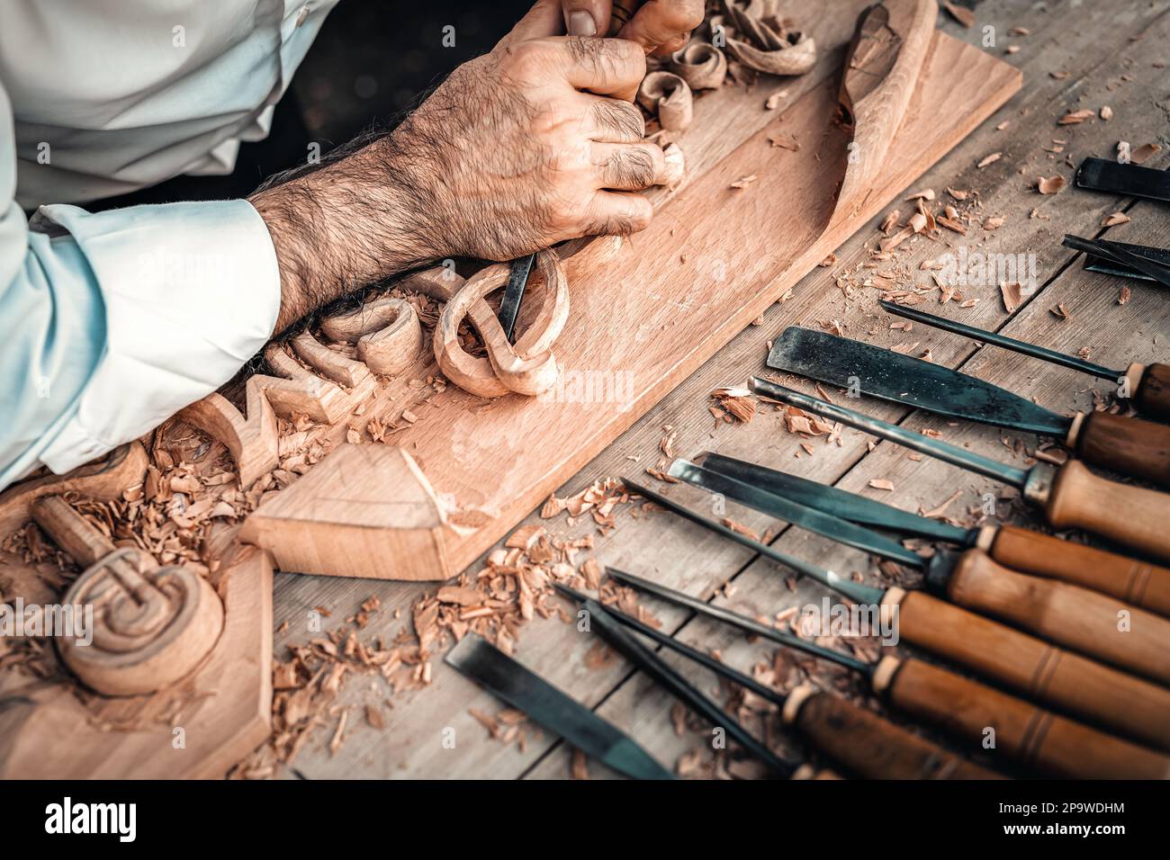 Ein Holzarbeiter, der Holz auf den Tisch schneidet. Holzarbeitertisch mit Schneidern und Werkzeugen. Zimmermann mit Meißel. Stockfoto