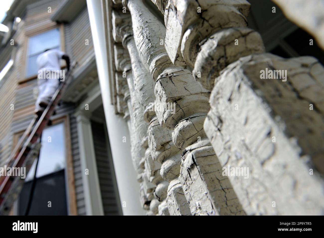 The lead paint flakes and cracks on the spindles of a porch as a