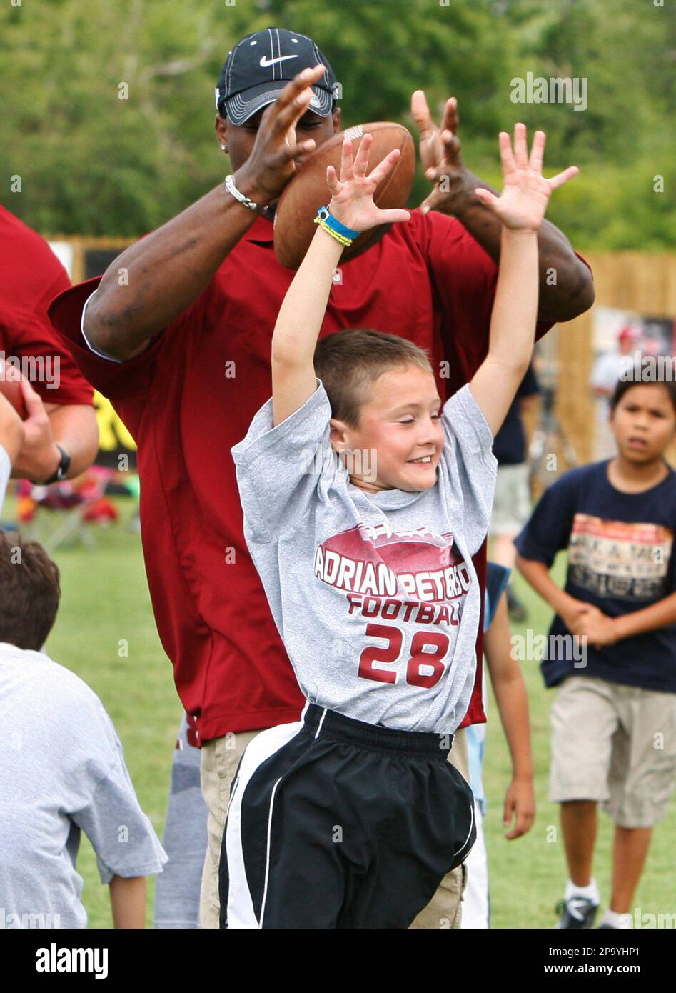 Eight-year-old Hayden Whitaker, right, jumps up to attempt to block a pass intended for former Oklahoma running back Adrian Peterson, left, now with the Minnesota Vikings, at Peterson's football camp in Norman, Okla., Friday, June 27, 2008. (AP Photo) Stockfoto