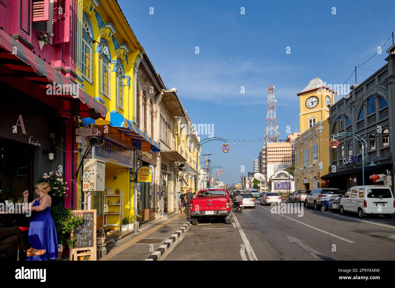 Farbenfrohe Geschäfte im chinesisch-portugiesischen Stil in der Phang-Nga Rd In der Altstadt von Phuket Town, Thailand, mit dem berühmten Phromthep Clocktower in b/g Stockfoto